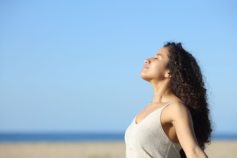 Woman with good skincare walking along beach with Iv infusion.