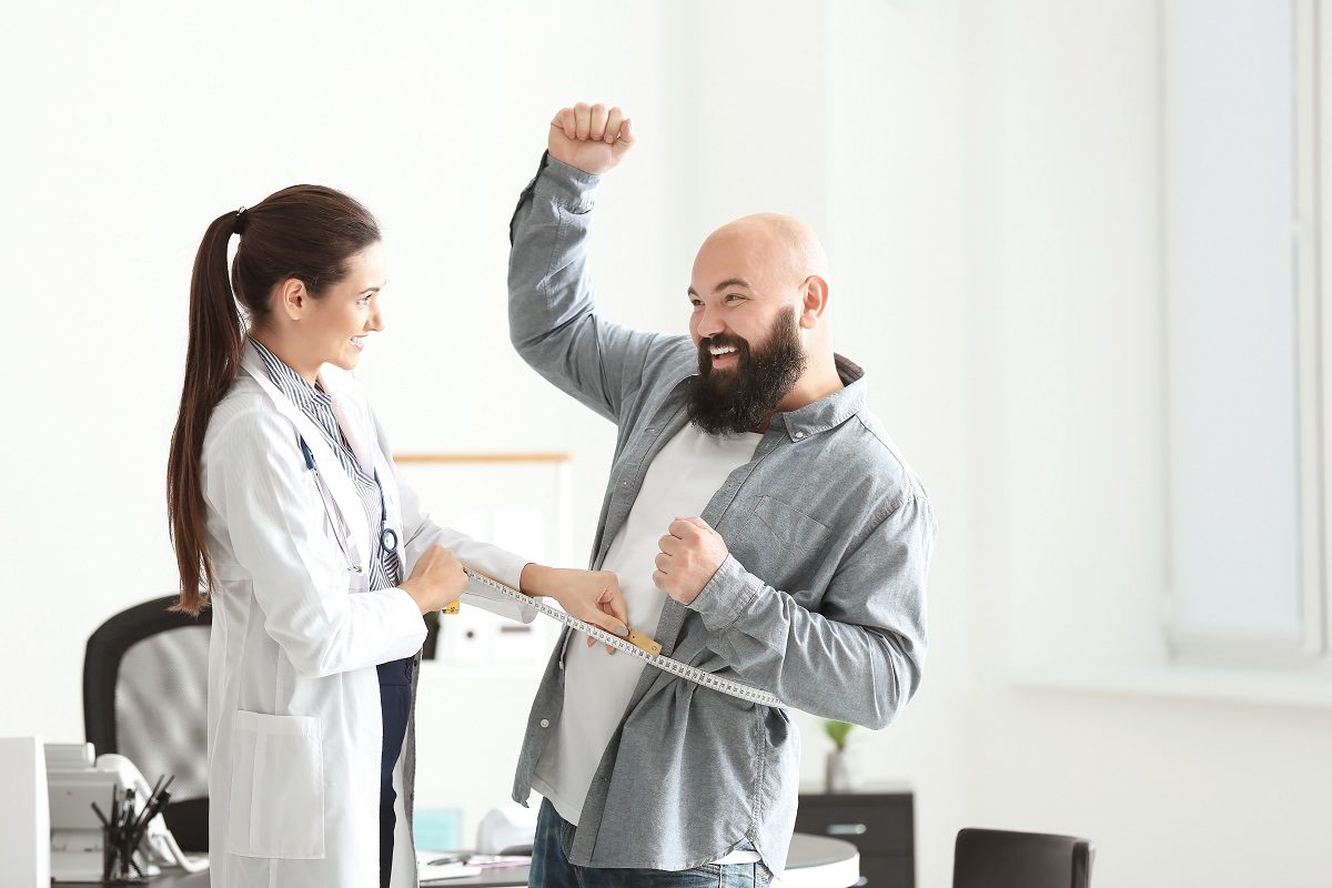 Man is excited as he gets his waist measured by a medical professional.