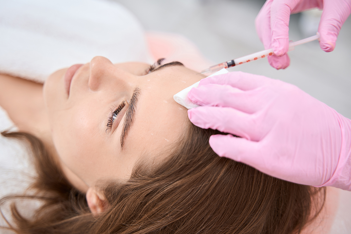 A health professional injecting a syringe into a woman's forehead