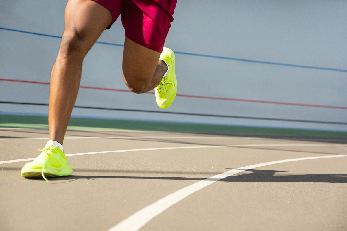 Fit male athletes legs running on a track at the stadium